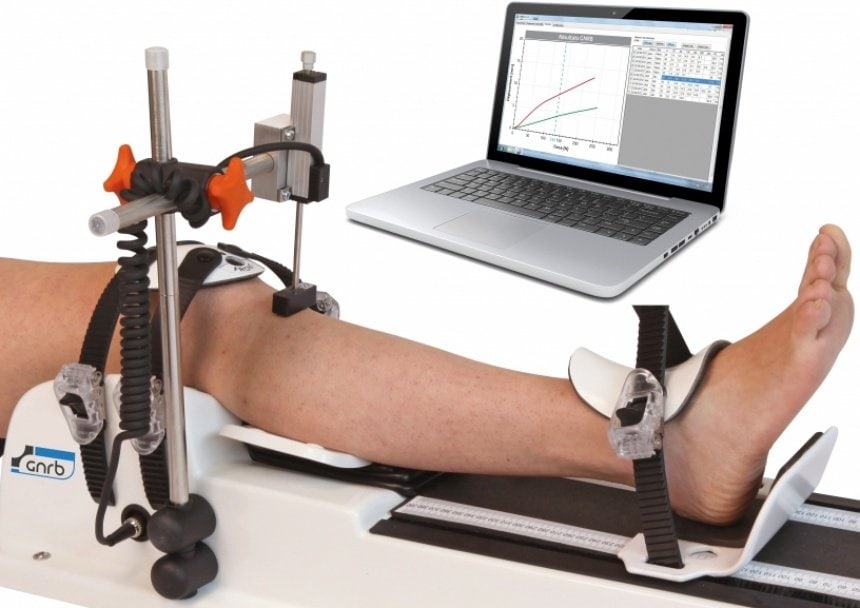 Knee arthrometer: a leg strapped in the GNRB next to a laptop.