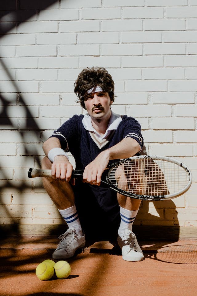 a man sitting with his tennis racket