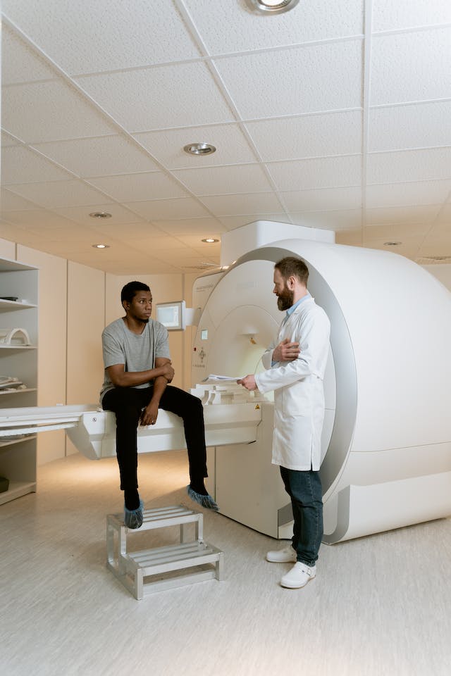 a radiologist talking to a patient next to an MRI