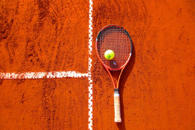 a tennis ball and raquet on clay